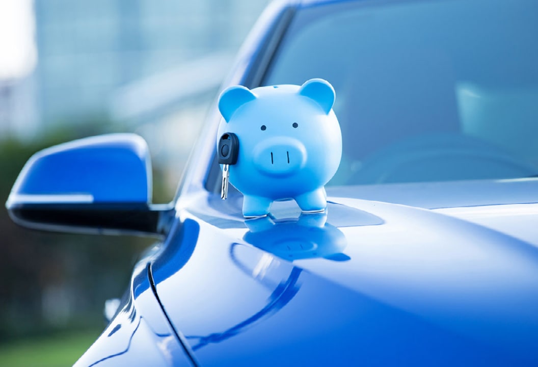 Blue piggy bank with car key on blue car.